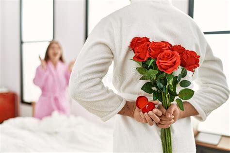 man surprising his girlfriend with bouquet of roses at bedroom stock image image of bedroom