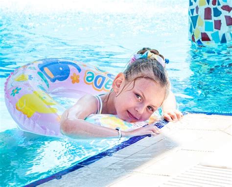 Маленькая девочка плавает с кругом в бассейне Премиум Фото