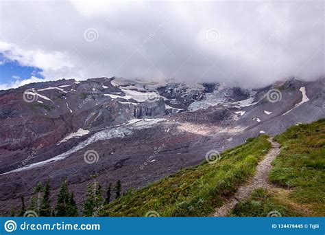Green Meadow With Path Leading Up Mountain To Snow Field Stock Image