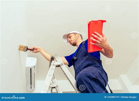 Young Man Painting A Wall On A White Color Background In A Modern Home