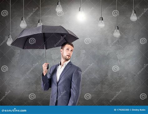 Surprised Businessman With Umbrella With Bulbs Above Head Stock Photo
