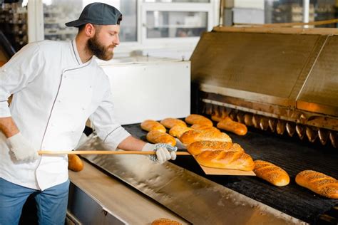 Premium Photo A Baker Picks Up Hot Bread From A Industrial Oven With