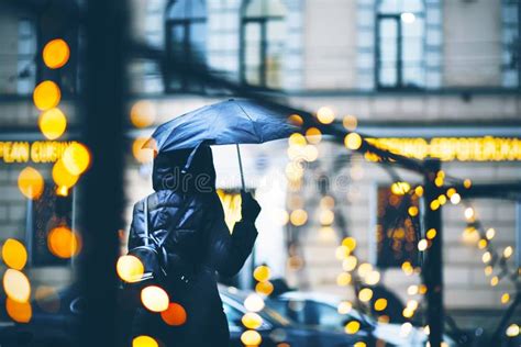 A Girl In A Windbreaker With A Wet Umbrella Walks Along A City Street