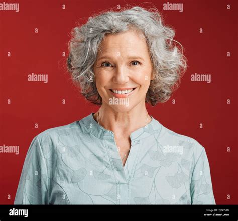 Portrait Of Senior Happy And Cheerful Woman Standing Against A Red