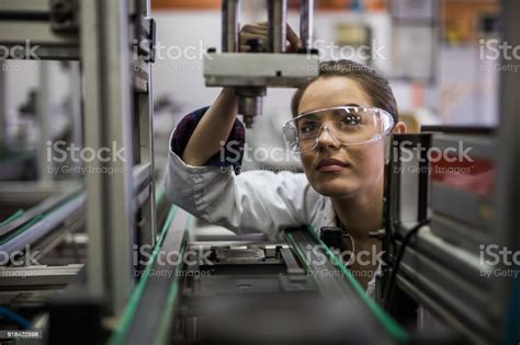 Female Engineer Examining Machine Part On A Production Line Stock Photo