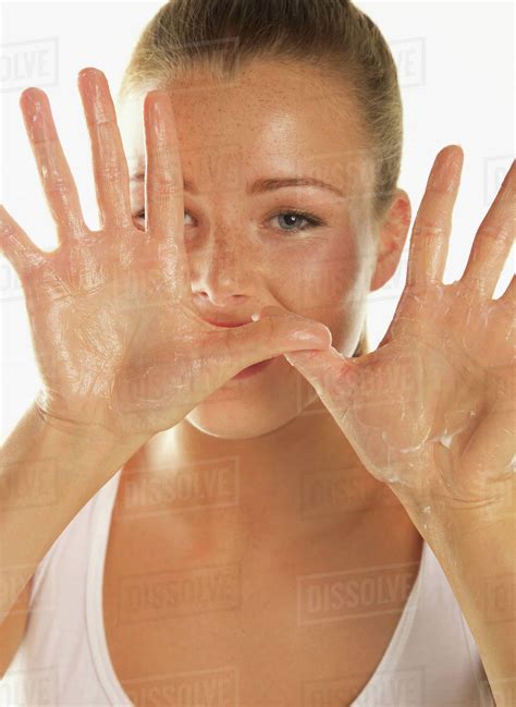 Close Up Portrait Of Beautiful Woman Showing Body Lotion On Palms Against White Background