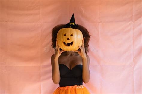 молодая американка в костюме ведьмы для вечеринки на ней оранжевая юбка в колдовской шляпе
