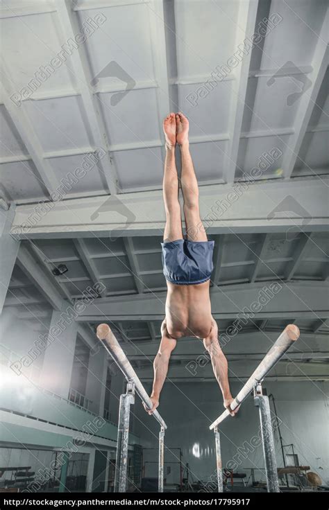 Male Gymnast Performing Handstand On Parallel Bars Stock Photo