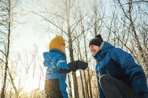 Vista De Bajo ángulo De Padre E Hijo Jugando Con Nieve Contra árboles