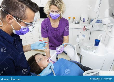 Dentist With Assistant Examining Patient In Dentistry Stock Image