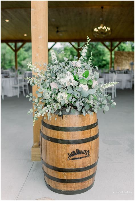 white arrangement with mixed greenery rustic whiskey barrell wild hill flowers and events