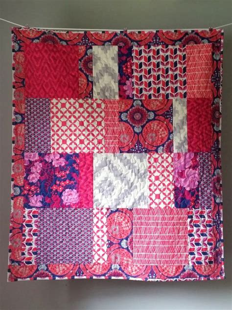 A Pink And Red Patchwork Quilt Hanging On A Wall