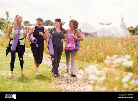 Group Of Mature Female Friends On Outdoor Yoga Retreat Walking Along Path Through Campsite Stock