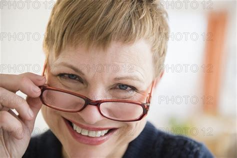 caucasian woman peering over eyeglasses photo12 tetra images jgi jamie grill