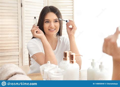Beautiful Woman Applying Oil Onto Her Eyelashes Near Mirror Stock Photo