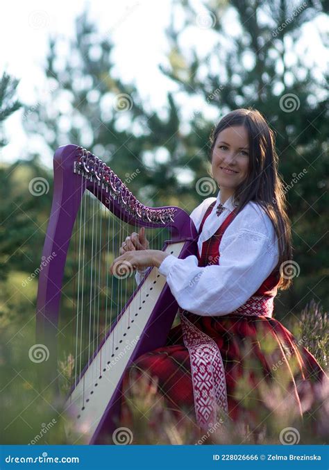 Beautiful Young Woman Playing Celtic Harp And Singing Song In Woodland