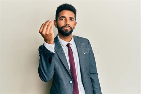 Handsome Hispanic Man With Beard Wearing Business Suit And Tie Doing Italian Gesture With Hand