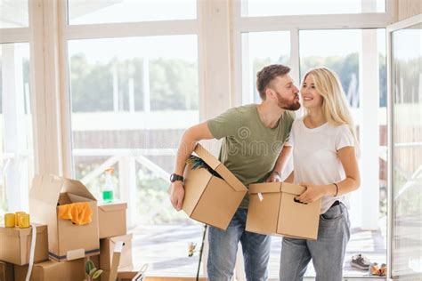 Happy Couple Carrying Cardboard Boxes Into New Home On Moving Day Stock