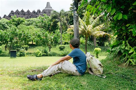Anak Lakilaki Duduk Di Rumput Saat Bepergian Di Candi Borobudur Jawa