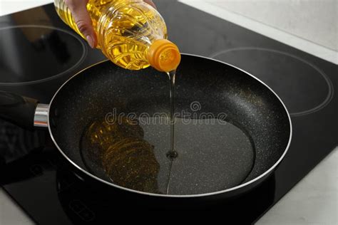 Woman Pouring Cooking Oil Into Frying Pan On Stove Closeup Stock Photo