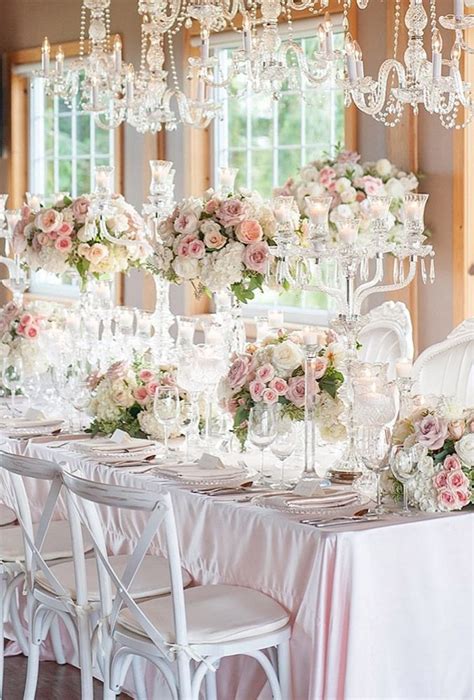 A Dining Room Table Is Set With Flowers And Chandeliers For An Elegant