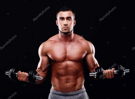 Сексуальный мускулистый мужчина тренируется с гантелями на черном фоне