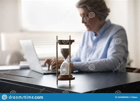 Mature Businesswoman Work On Laptop Hourglass On Table Forefront View