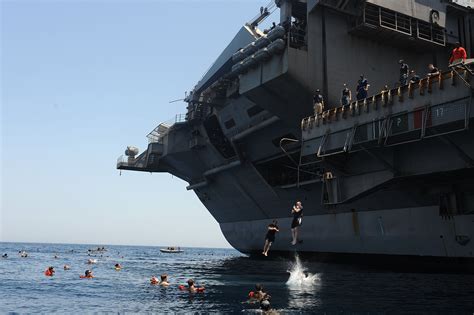 Sailors Jump From An Aircraft Elevator During A Swim Call Aboard The
