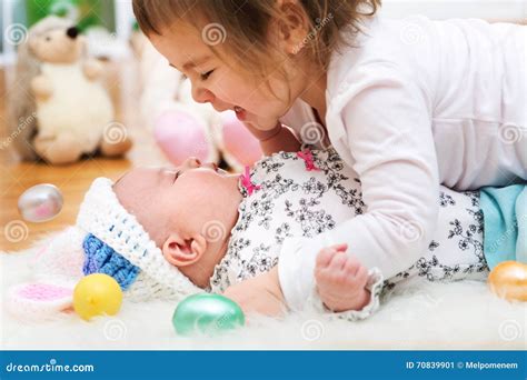 Happy Toddler Girl Playing With Her Baby Sister On Easter Stock Image