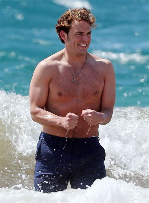 A Shirtless Man Standing In The Water At The Beach With His Hand On His Hip