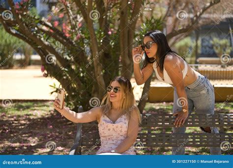 Two Young Women Beautiful Brunette And Blonde South Americans With Sunglasses Sitting On A