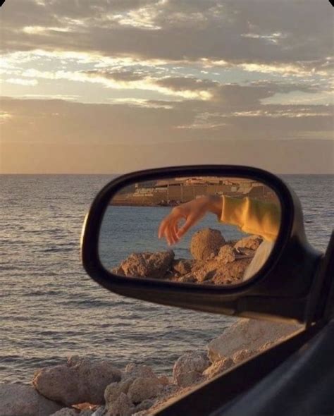 A Persons Reflection In The Side View Mirror Of A Car Near The Ocean