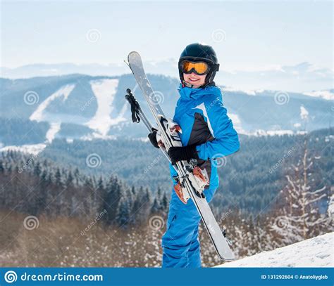 Happy Female Skier Smiling To The Camera Holding Her Skis Wearing