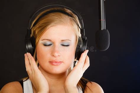 Woman Singing To Microphone Wearing Headphones In Studio Stock Photo