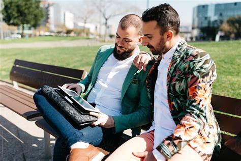 Gay Couple Browsing Pad On Bench By Stocksy Contributor Guille Faingold Stocksy