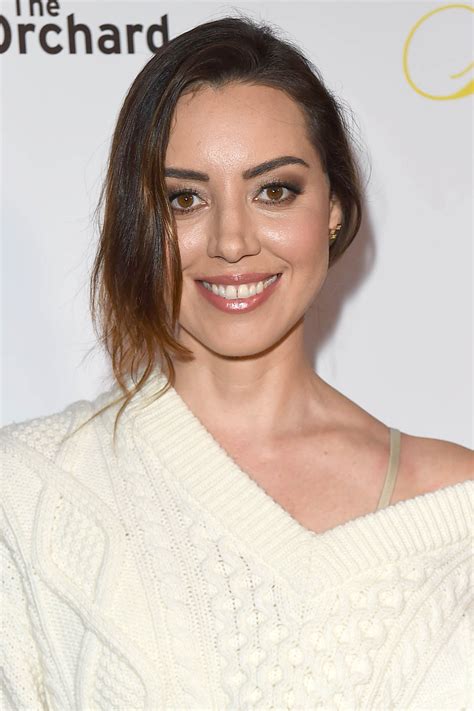 a smiling woman in a white sweater posing for the camera with her hair pulled back