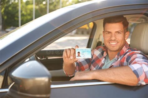 Happy Man Holding License While Sitting In Car Outdoors Driving School
