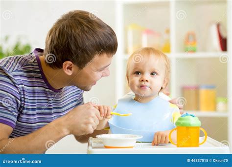 El Padre Joven Enseña A Su Hijo Del Bebé A Comer Con Imagen De Archivo