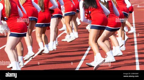 High School Cheerleaders Wearing Red Uniforms Cheering On The Sidelines