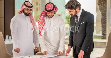 رجل اعمال عربي سعودي خليجي بالثوب السعودي التقليدي يقوم بتوقيع اتفاقية عمل لمشروع جديد مع عميل