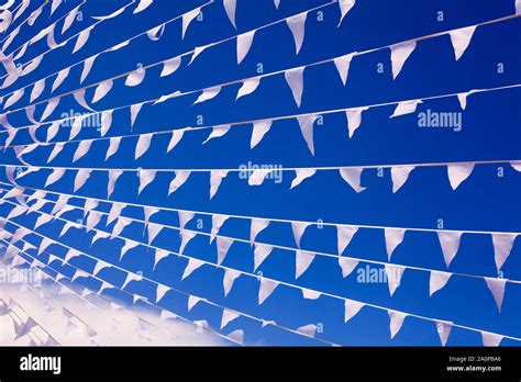 White Triangular Flags Waving In Wind Blue Sky Background Close Up