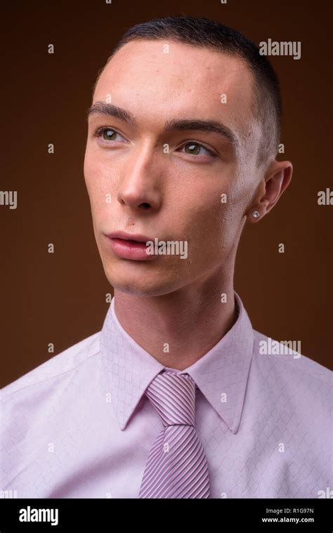 Young Handsome Androgynous Businessman Against Brown Background Stock