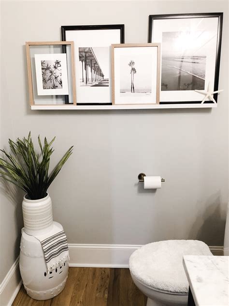 A White Toilet Sitting Next To A Bathroom Wall With Pictures On The