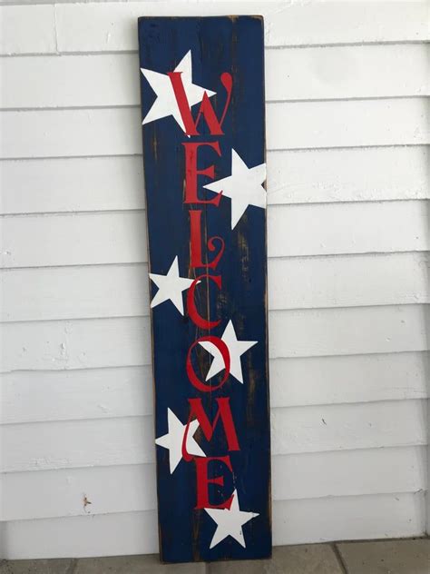 A Wooden Sign That Says Welcome Home With White Stars On Blue And Red