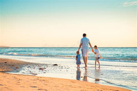 Padre Con Dos Hijos Que Caminan En La Playa Foto De Archivo Imagen De