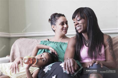 Happy Lesbian Couple With Daughter On Living Room Sofa — Juice