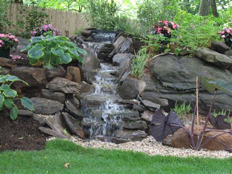 A Small Waterfall In The Middle Of A Garden