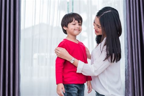 La Mamá Asiática Joven Vistió La Camisa Del Hijo Para Preparar Va A La