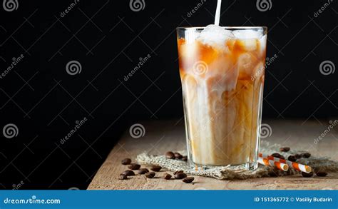Ice Coffee In A Tall Glass With Cream Poured Over Ice Cubes And Beans