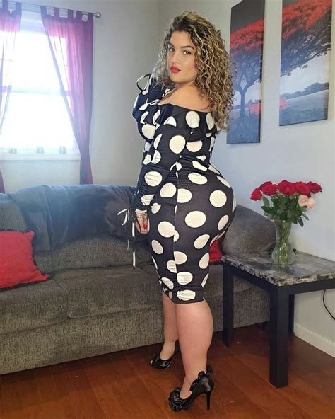 A Woman Standing In Front Of A Couch Wearing Polka Dot Dress And High Heeled Shoes